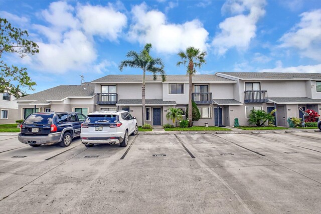 multi unit property with stucco siding, uncovered parking, and a balcony