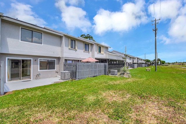 rear view of property with stucco siding, fence, a yard, and central AC unit