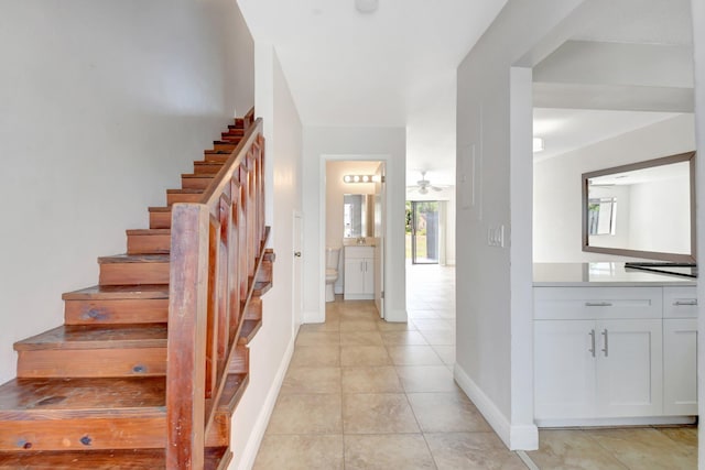 staircase with baseboards, ceiling fan, and tile patterned flooring