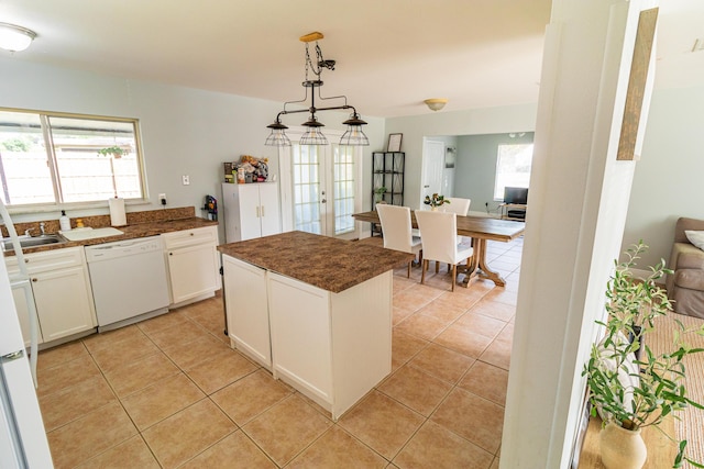 kitchen with light tile patterned floors, a center island, dark countertops, dishwasher, and white cabinets