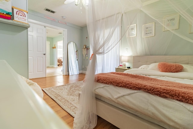 bedroom featuring wood finished floors, visible vents, and ceiling fan