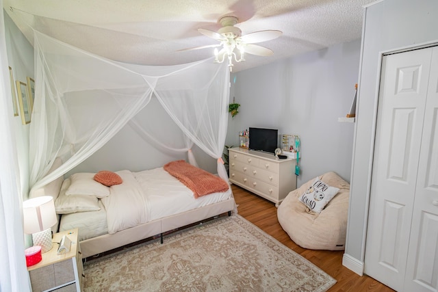 bedroom with wood finished floors, ceiling fan, and a textured ceiling