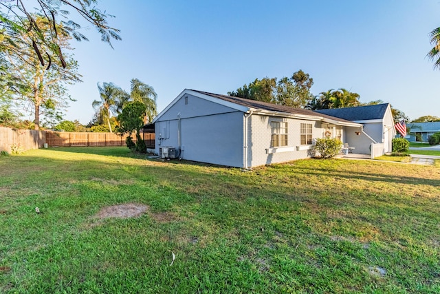 exterior space featuring fence, cooling unit, and a yard
