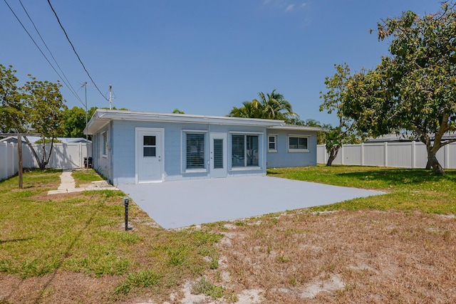 712 NE Camino St, Port Saint Lucie, FL 34952 - back of property with a lawn, a fenced backyard, and a patio area