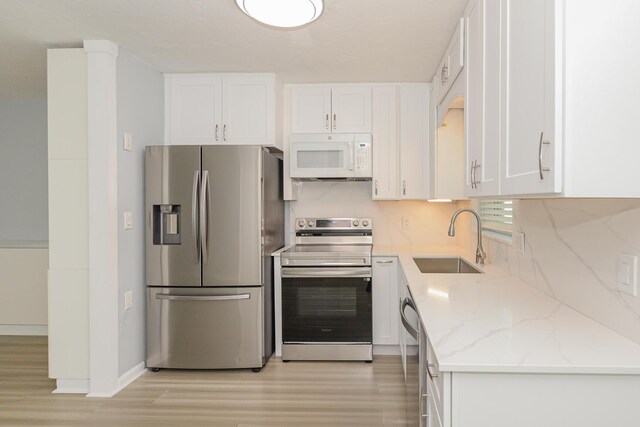 712 NE Camino St, Port Saint Lucie, FL 34952 - kitchen featuring a sink, light wood-style floors, stainless steel appliances, and white cabinetry