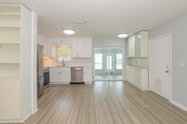 712 NE Camino St, Port Saint Lucie, FL 34952 - kitchen featuring light countertops, white cabinetry, tasteful backsplash, a sink, and stainless steel appliances