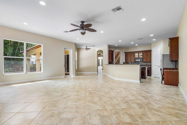 unfurnished living room with recessed lighting, arched walkways, ceiling fan, and visible vents