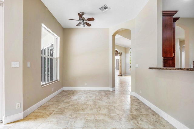 spare room featuring visible vents, ceiling fan, baseboards, and arched walkways