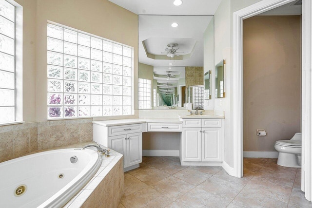 bathroom featuring ceiling fan, baseboards, toilet, a whirlpool tub, and vanity