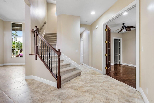 stairs featuring ceiling fan, baseboards, and arched walkways