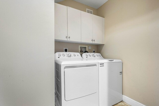 clothes washing area featuring baseboards, visible vents, cabinet space, and independent washer and dryer