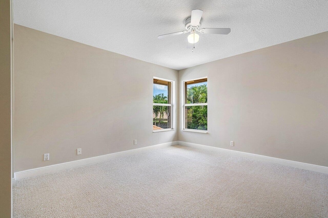 carpeted empty room featuring baseboards, ceiling fan, and a textured ceiling