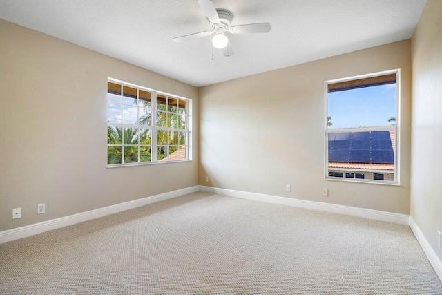 carpeted spare room featuring a textured ceiling, ceiling fan, and baseboards