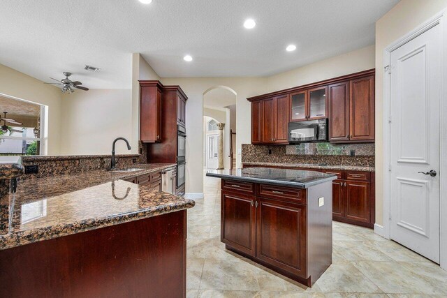 6616 Cobia Cir, Boynton Beach, FL 33437 - kitchen with black appliances, a sink, reddish brown cabinets, ceiling fan, and arched walkways