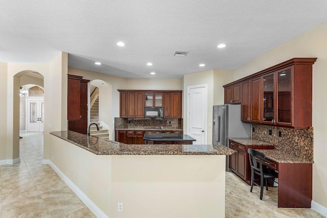 6616 Cobia Cir, Boynton Beach, FL 33437 - kitchen featuring arched walkways, black microwave, a peninsula, backsplash, and dark stone countertops