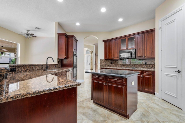 kitchen featuring a sink, arched walkways, black appliances, a ceiling fan, and reddish brown cabinets