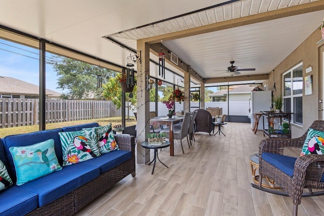sunroom with a ceiling fan, an outdoor living space, and outdoor dining area