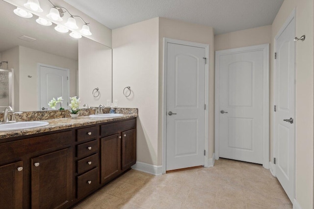 full bathroom with double vanity, baseboards, tile patterned flooring, and a sink