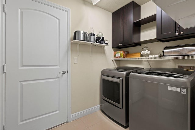 laundry room with light tile patterned flooring, separate washer and dryer, cabinet space, and baseboards