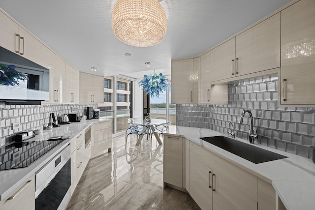 525 S Flagler Dr Unit 16A, West Palm Beach, FL 33401 - kitchen featuring backsplash, wall oven, a sink, stainless steel microwave, and a notable chandelier