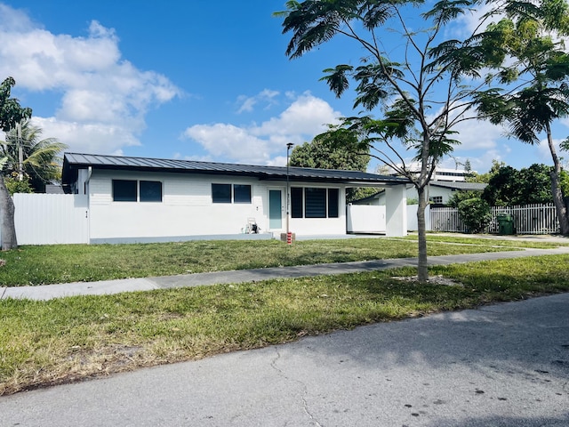 4730 W 8th Pl, Hialeah, FL 33012 - ranch-style house with a standing seam roof, fence, a front lawn, and metal roof
