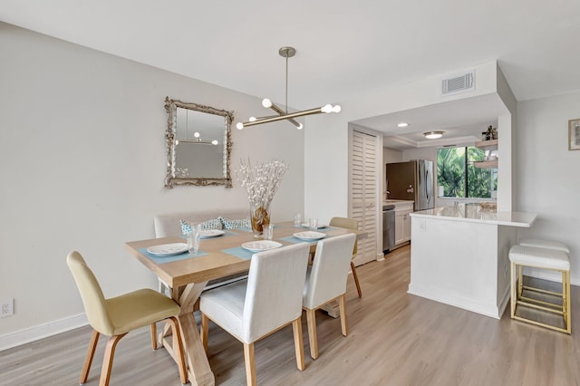dining area featuring visible vents, a notable chandelier, baseboards, and light wood-style floors
