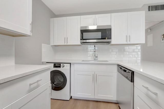296 Fanshaw H, Boca Raton, FL 33434 - kitchen with washer / dryer, stainless steel appliances, a sink, backsplash, and white cabinetry