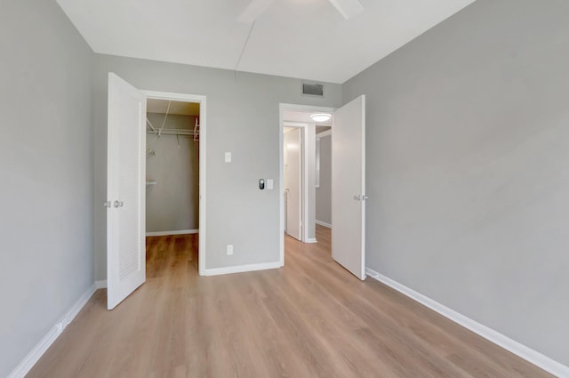 296 Fanshaw H, Boca Raton, FL 33434 - unfurnished bedroom with light wood-type flooring, a spacious closet, a closet, and baseboards