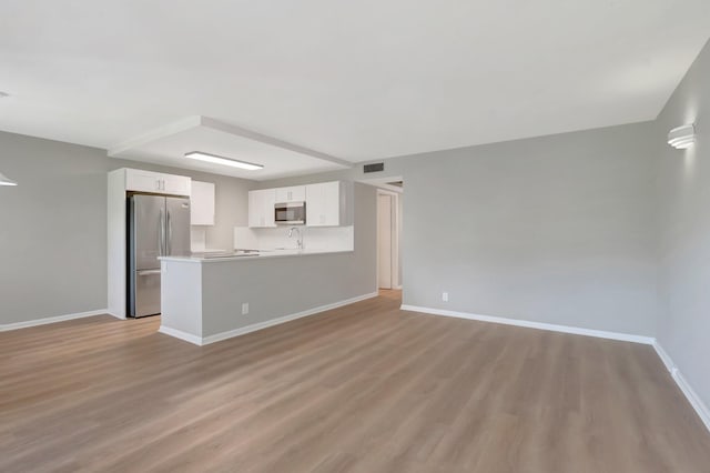 296 Fanshaw H, Boca Raton, FL 33434 - unfurnished living room with baseboards, light wood-style flooring, and a sink