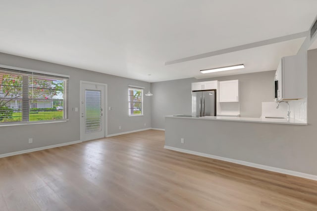 296 Fanshaw H, Boca Raton, FL 33434 - unfurnished living room with light wood-style floors, a sink, and baseboards
