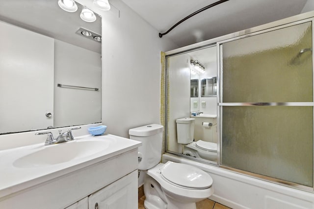 bathroom featuring toilet, combined bath / shower with glass door, tile patterned flooring, and vanity
