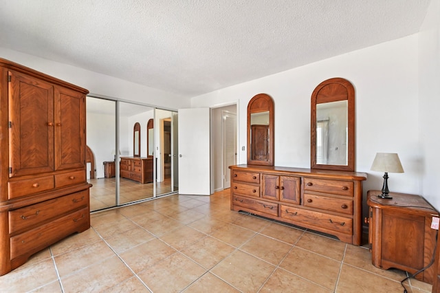 bedroom featuring a closet, a textured ceiling, and light tile patterned flooring