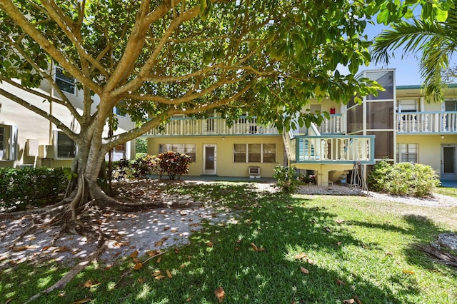 rear view of house featuring a lawn and stucco siding