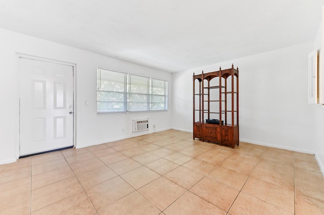 spare room featuring light tile patterned flooring, baseboards, and a wall unit AC