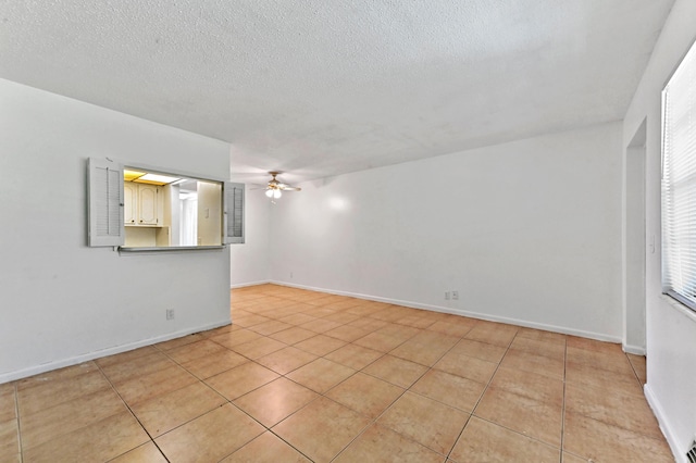 unfurnished room featuring a textured ceiling, ceiling fan, and light tile patterned floors