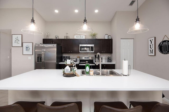 kitchen featuring a kitchen breakfast bar, a sink, visible vents, stainless steel appliances, and light countertops