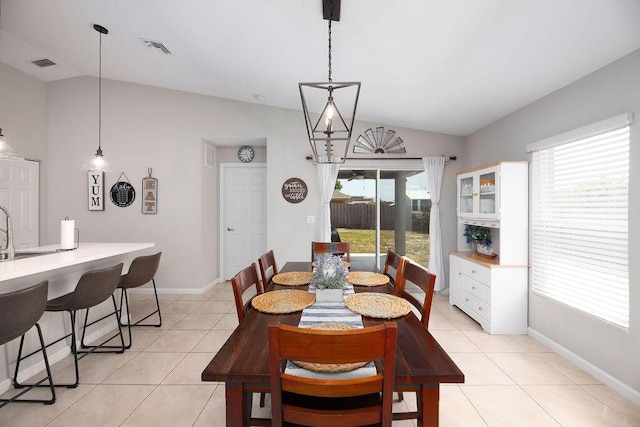 dining area featuring light tile patterned floors, visible vents, vaulted ceiling, and baseboards