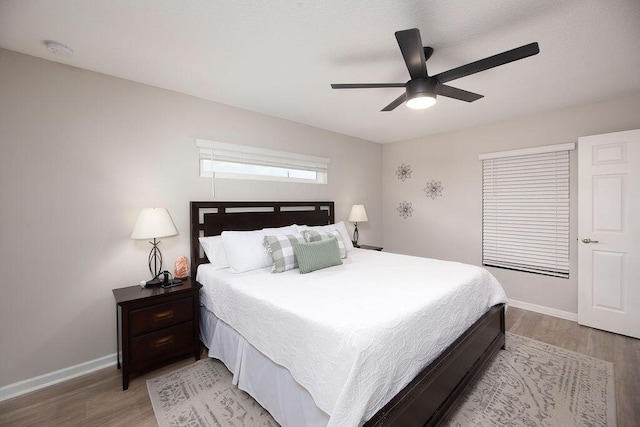 bedroom with ceiling fan, baseboards, and light wood-style floors