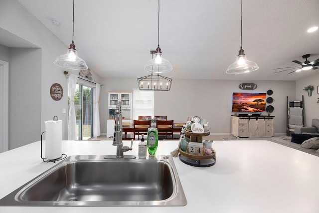 kitchen with hanging light fixtures, a sink, open floor plan, and light countertops