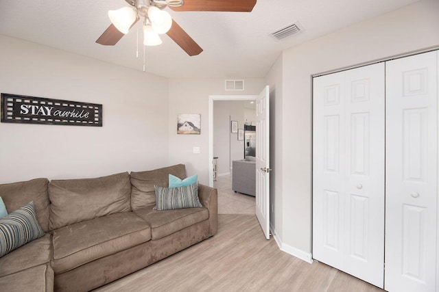 living room with light wood finished floors, visible vents, ceiling fan, and baseboards