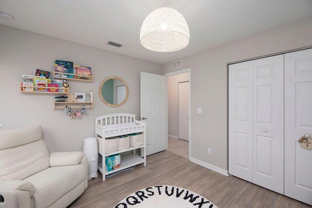 bedroom with a closet, a notable chandelier, visible vents, baseboards, and wood finished floors