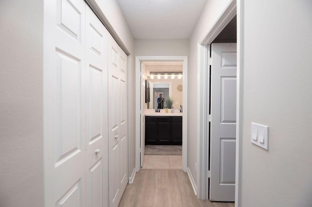 hall with a textured ceiling and light wood-style flooring