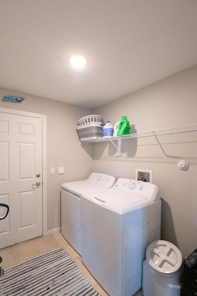 clothes washing area featuring light tile patterned floors, washer and clothes dryer, and laundry area