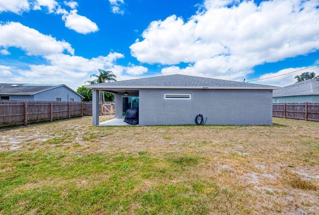 rear view of property with a patio, ceiling fan, a fenced backyard, a lawn, and stucco siding
