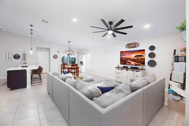 living area featuring light tile patterned flooring, recessed lighting, baseboards, and ceiling fan with notable chandelier