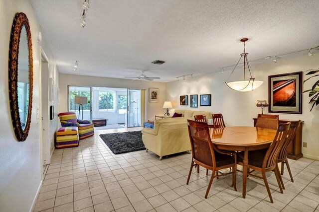 dining area featuring light tile patterned floors, a ceiling fan, rail lighting, and visible vents