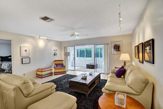 living area featuring visible vents, rail lighting, a textured ceiling, and ceiling fan