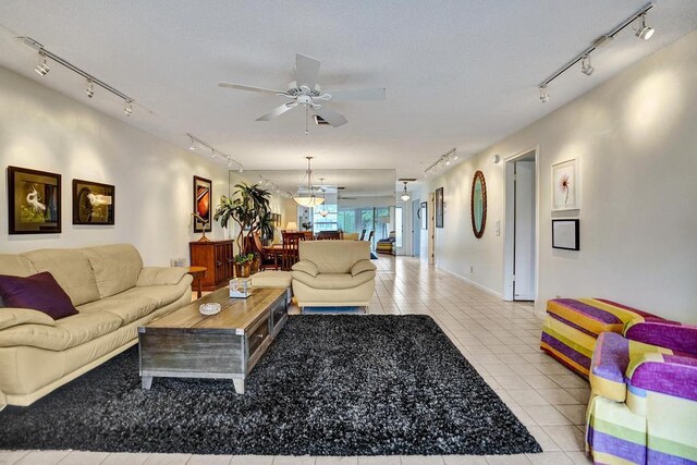 living room with baseboards, rail lighting, ceiling fan, and light tile patterned floors