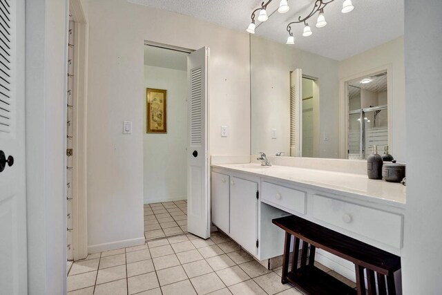 bathroom with vanity, baseboards, a closet, and tile patterned floors