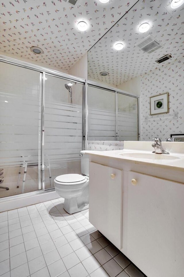 bathroom with tile patterned flooring, vanity, toilet, wallpapered walls, and a shower stall